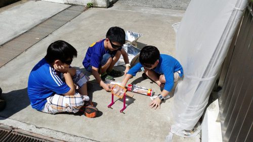 Shin Jen’s workshop with 3 children working on the solar cooker outdoors